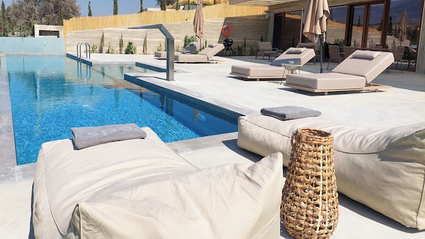 Ett område vid poolen med solstolar, en liten pool och en pergola.