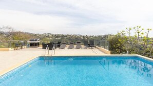 A swimming pool with lounge chairs and a barbecue area, surrounded by a fence and overlooking a hilly landscape. - Spacious, quiet Villa Niçoise with swimming pool (Nice)