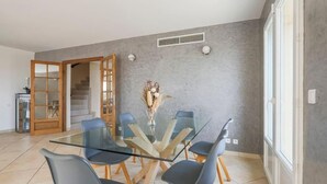 A modern dining area with a glass table and chairs, a staircase, and a view of the outdoors. - Spacious, quiet Villa Niçoise with swimming pool (Nice)