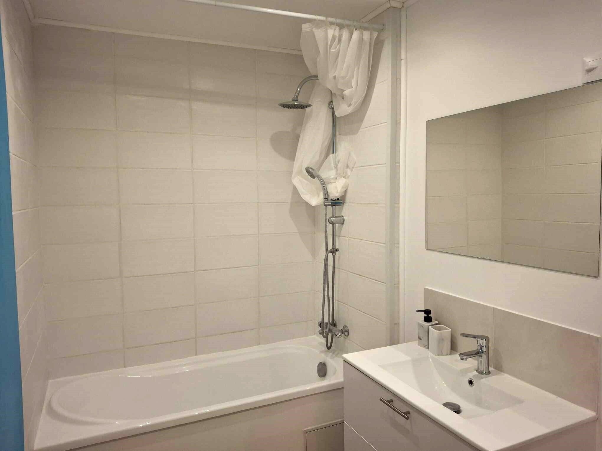 A modern bathroom with a bathtub, a shower, and a sink with a mirror.