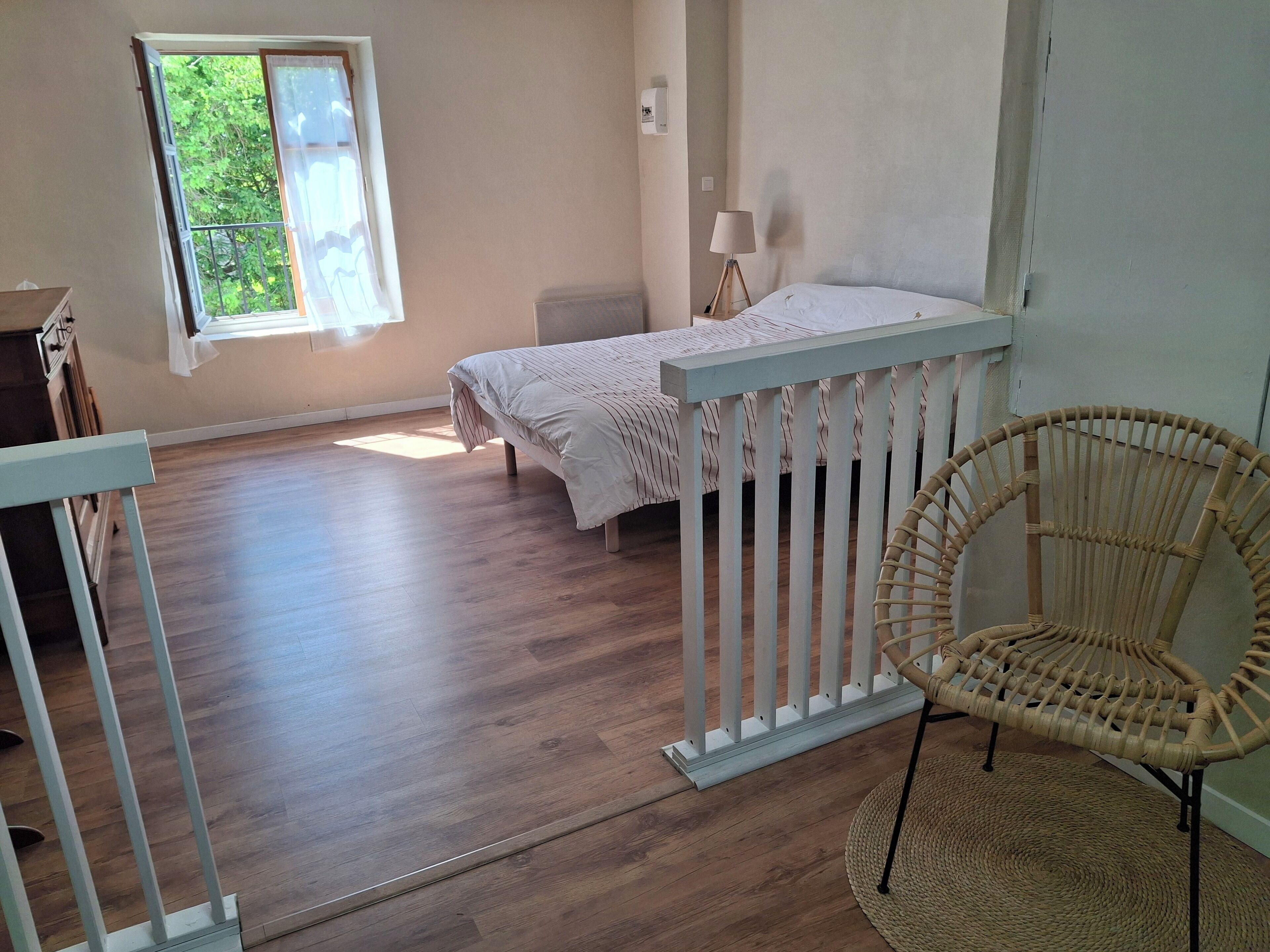 A bedroom with a bed, a chair, a window, and a lamp.