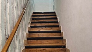 Eine Holztreppe mit Handlauf, die zu einem Raum mit einem runden Spiegel an der Wand führt.