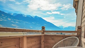 A wooden balcony with two white wicker chairs, a wooden railing, and a view of snow-capped mountains under a clear sky. - Lebe'schlitters - Im Zillertal (Schlitters)