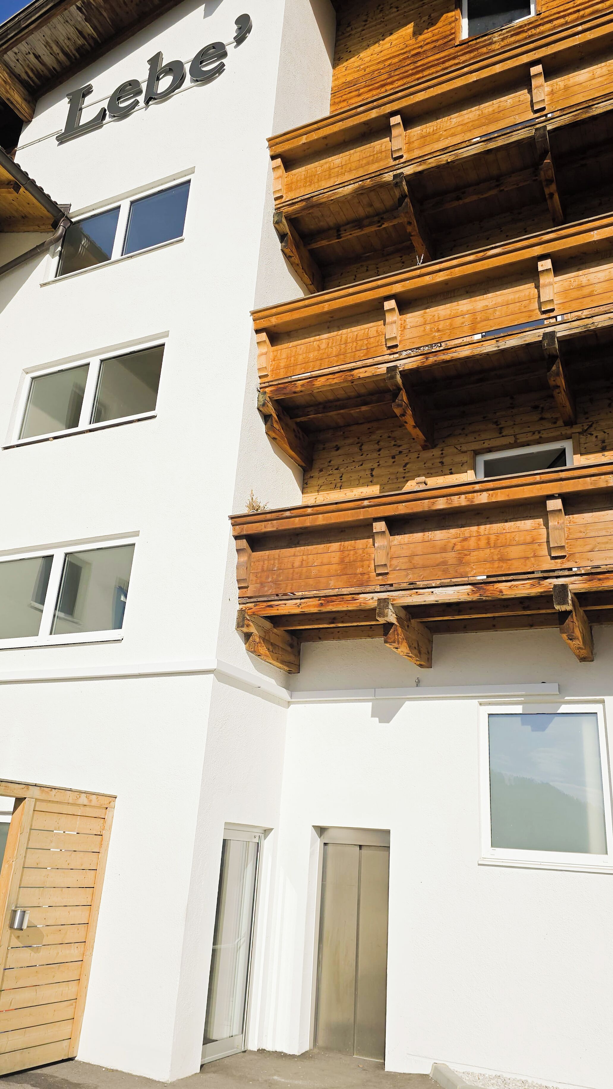 A multi-story building with the name 'Lebe' on the facade. It features balconies with wooden railings and multiple windows.