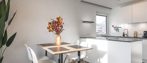A modern kitchen with a central island, white cabinetry, and a dining area with a table and chairs.