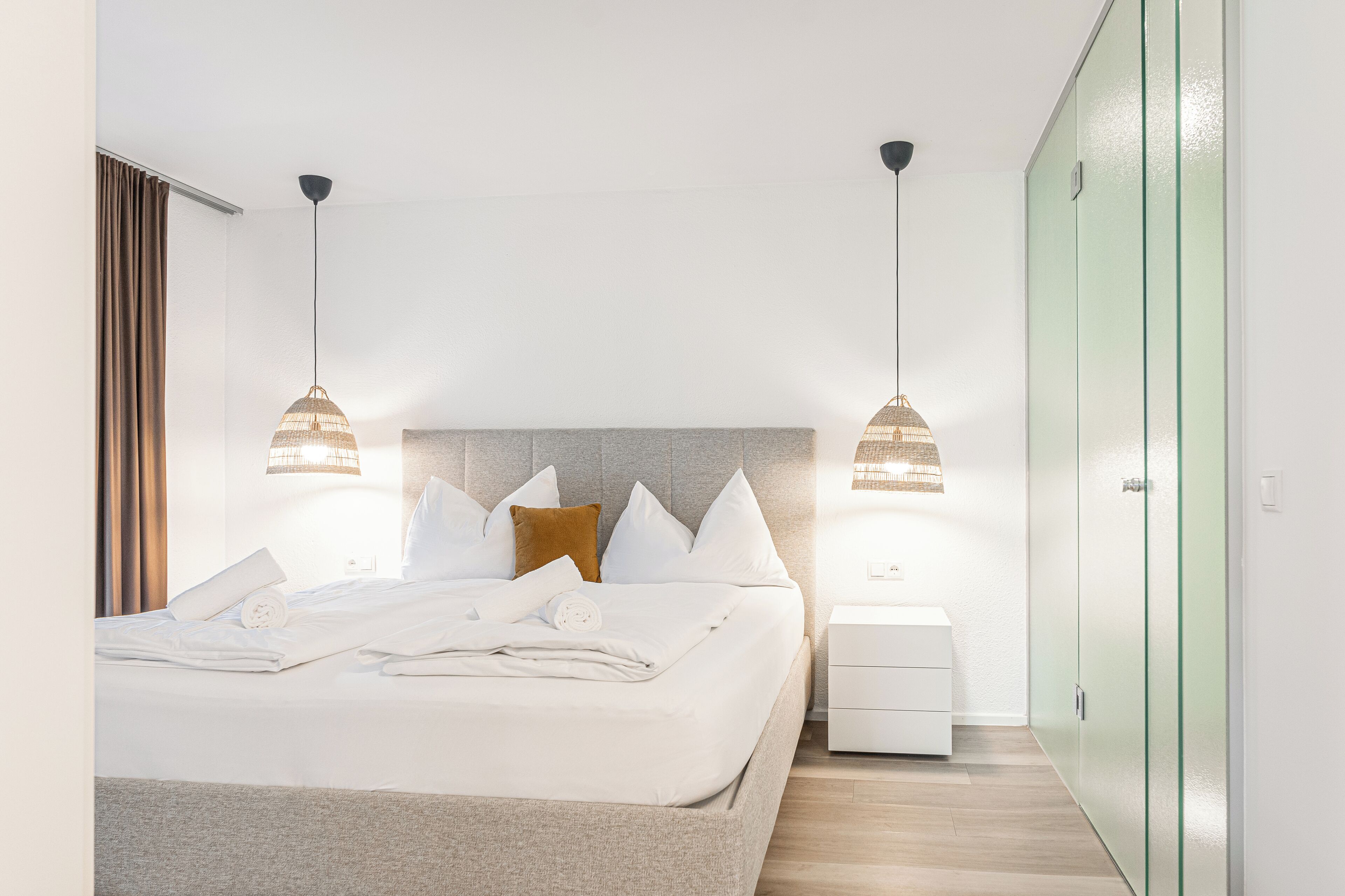 Une chambre d’hôtel moderne avec un lit bien fait, deux lampes de chevet, une table de chevet et une armoire.