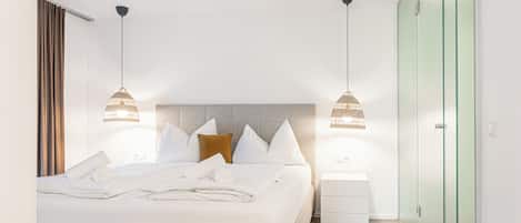 Une chambre d’hôtel moderne avec un lit bien fait, deux lampes de chevet, une table de chevet et une armoire.