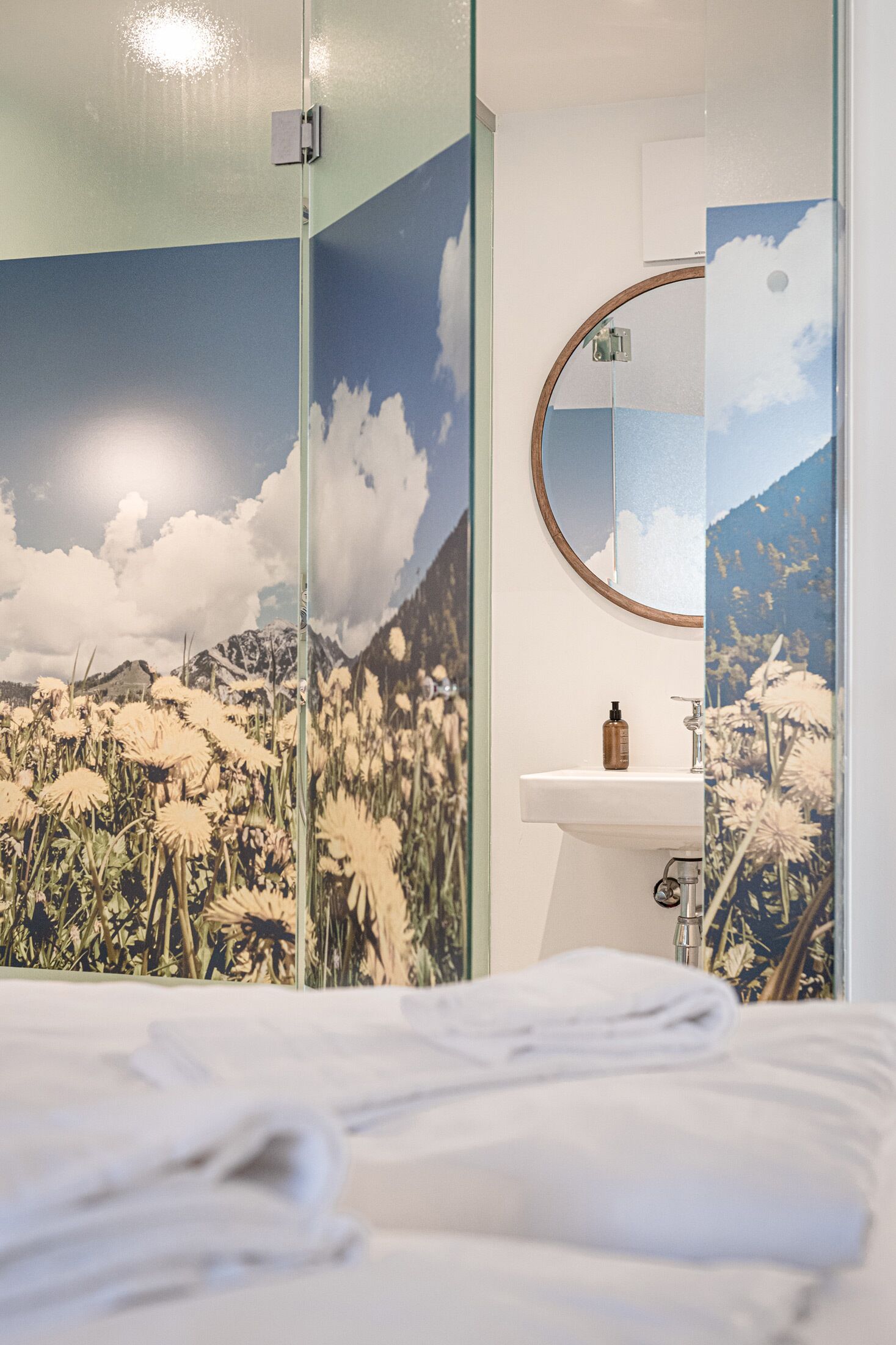 A hotel room with a bed, a white sink, and a mirror.