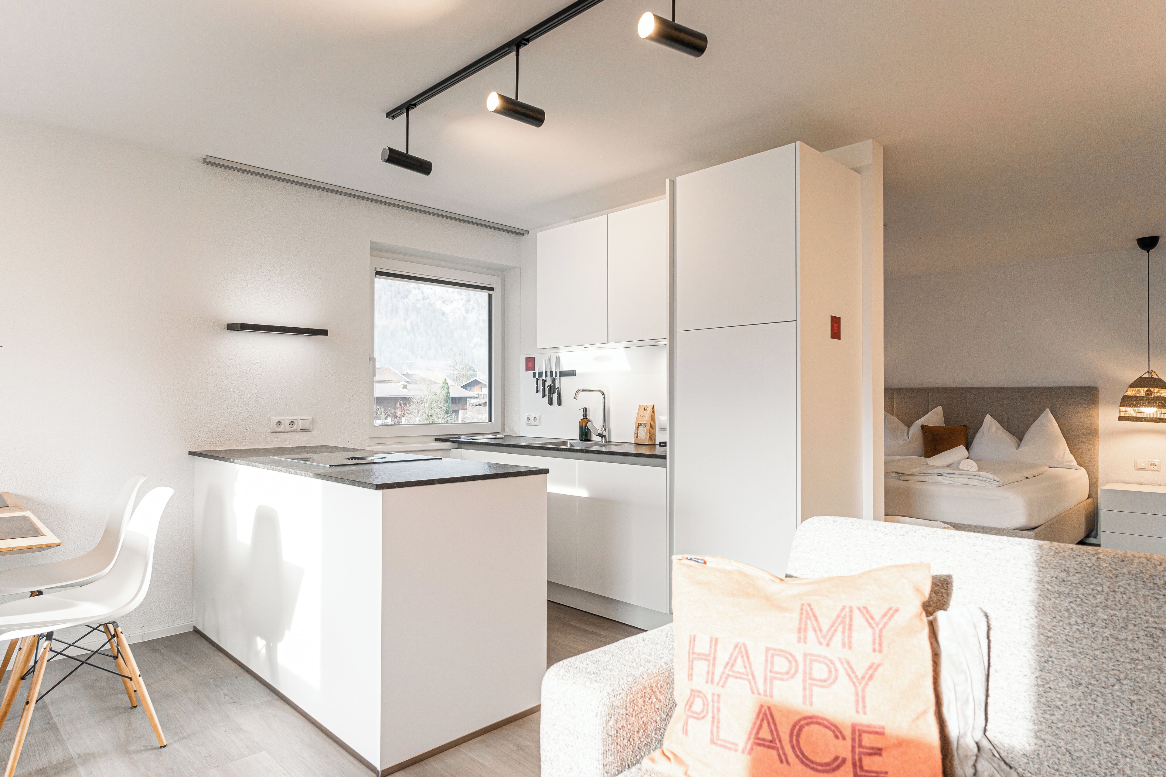 A modern kitchen with white cabinetry, a central island, and pendant lighting.
