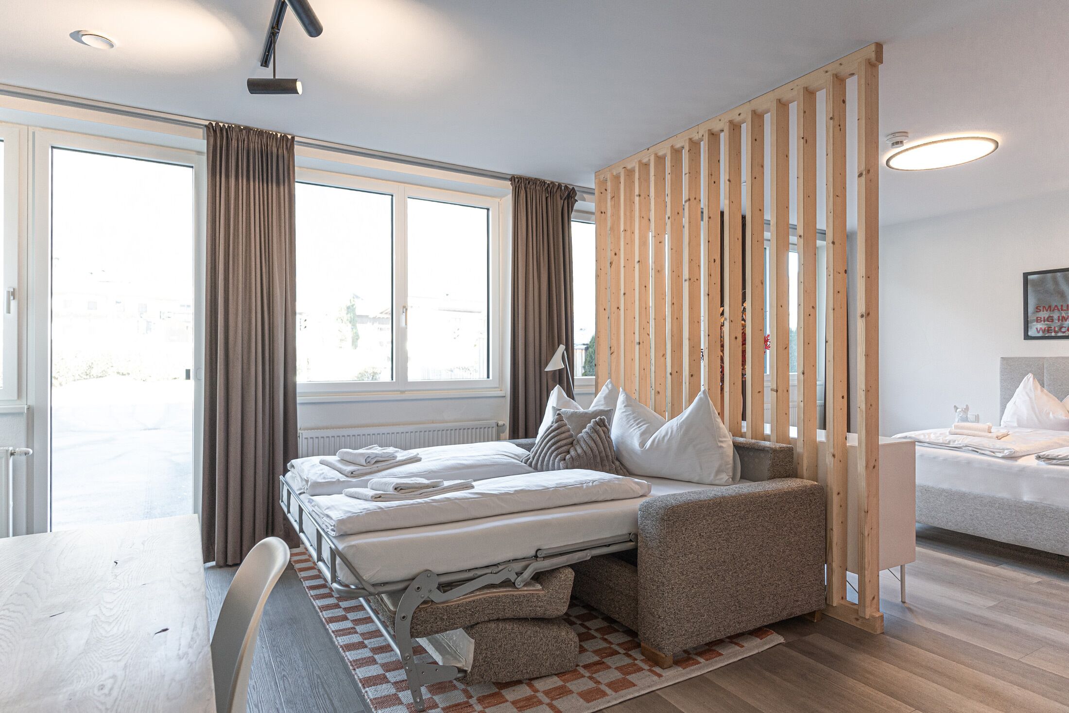Une chambre d’hôtel moderne équipée d’un lit, d’un canapé, d’une table à manger et d’une grande fenêtre.