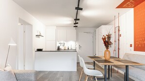 A modern kitchen with white cabinets, a central island, and a dining area with a table and chairs. - Lebe'schlitters - Im Zillertal (Schlitters)