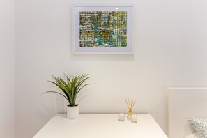 Simple, elegant space with a framed artwork, potted plant, and candles.