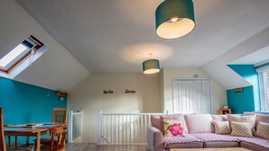 A cozy living room with a wooden dining table, a sofa, and a ceiling light fixture.