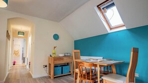 A dining area with wooden furniture, a clock on the wall, and a skylight.