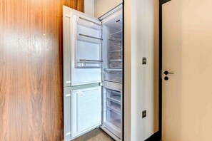 Uma cozinha moderna com frigorífico embutido, um armário de madeira e uma porta branca.