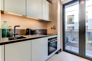 Eine moderne Küche mit schwarzem Arbeitsplatz, weißen Schränken und einem eingebauten Backofen.
