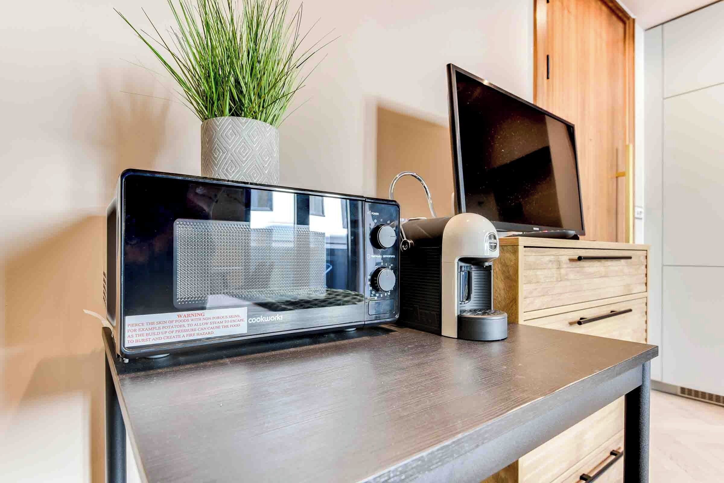 A modern kitchen with a portable microwave, a coffee maker, and a potted plant.
