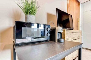 Uma cozinha moderna com micro-ondas portátil, cafeteira e um vaso com planta.