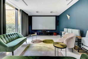 A modern living room with a sofa, armchairs, a coffee table, and a TV.