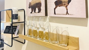 Two animal paintings on a wall, a shelf with wine glasses, and a metal rack with a sign. - HoneyComb GuestHouse (Rome)