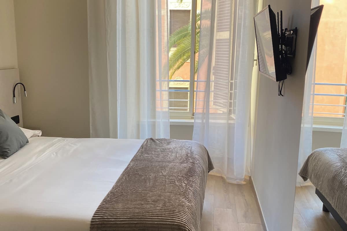 A hotel room with a bed, a sofa, a small table, and a TV mounted on the wall.