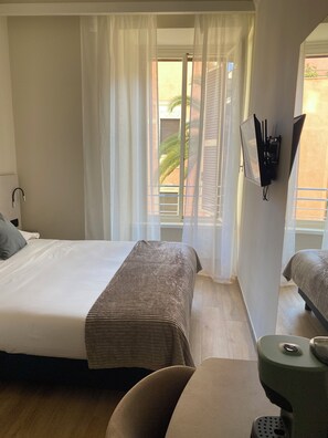 Et hotelværelse med en seng, en sofa, et lille bord og et tv ophængt på væggen.