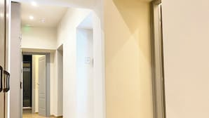 A spacious, well-lit hallway with wooden flooring and white walls, leading to multiple rooms. - HoneyComb GuestHouse (Rome)