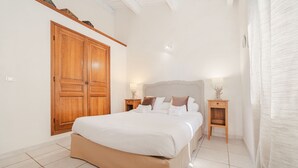 A bedroom with a large bed, wooden wardrobe, bedside tables, and a white curtain.