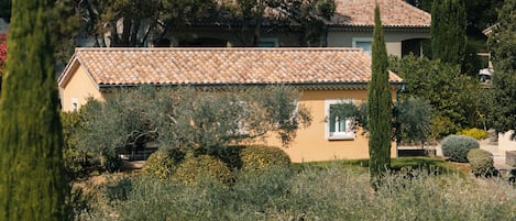 A building with a tiled roof, surrounded by trees and shrubs.