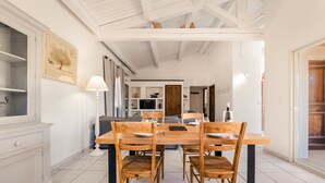 A dining area with a wooden table and chairs, a lamp, and a kitchen in the background.
