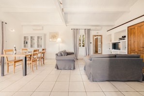 A spacious living area with a dining table, chairs, a sofa, and a television. - Villa Marselan - private pool and terrace (Saint-Maurice-d’Ardèche)