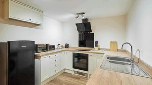 Una cucina compatta con un frigorifero nero, un forno a microonde, un tostapane, una macchina da caffè, un lavandino e un piano cottura.