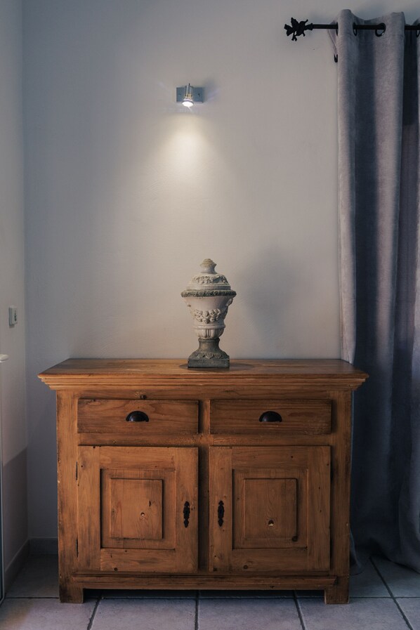 A wooden cabinet with two drawers, a wall-mounted light fixture, and a curtain rod.