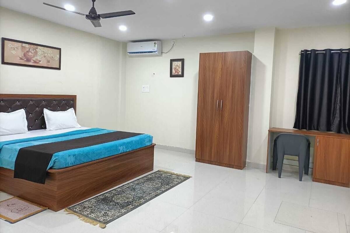 Un dormitorio con cama, armario, escritorio y ventilador de techo.