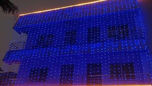 A building with a flat roof and multiple windows, illuminated with blue and orange lights.