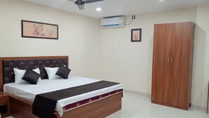 A bedroom with a bed, a wardrobe, a ceiling fan, and an air conditioning unit.