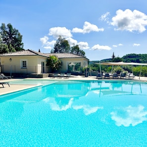 A clear blue pool with lounge chairs and a building in the background. - Villa Sémillon - private terrace and garden (Saint-Maurice-d’Ardèche)