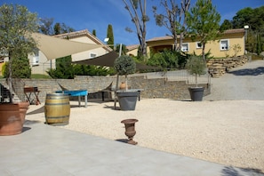 A courtyard with outdoor seating, a pergola, and a stone wall. - Villa Sémillon - private terrace and garden (Saint-Maurice-d’Ardèche)