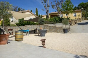 Un patio con mobiliario exterior, una pérgola y un muro de piedra.