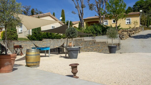 Une cour avec des sièges extérieurs, une pergola et un mur en pierre.