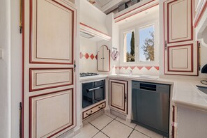 Una cocina compacta con armarios blancos, horno empotrado y lavavajillas.