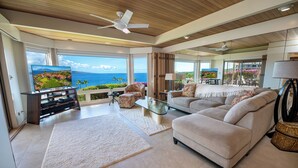 A spacious living room with a large TV, comfortable seating, and a view of the ocean. - Wailea Point Executive 2 Bedroom/3 Bath Oceanview Vacation Home (Wailea)