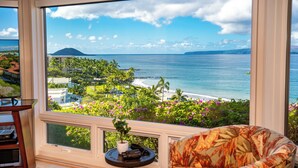 A balcony with a view of the ocean and a mountain, featuring a chair and a small table with a plant. - Wailea Point Executive 2 Bedroom/3 Bath Oceanview Vacation Home (Wailea)