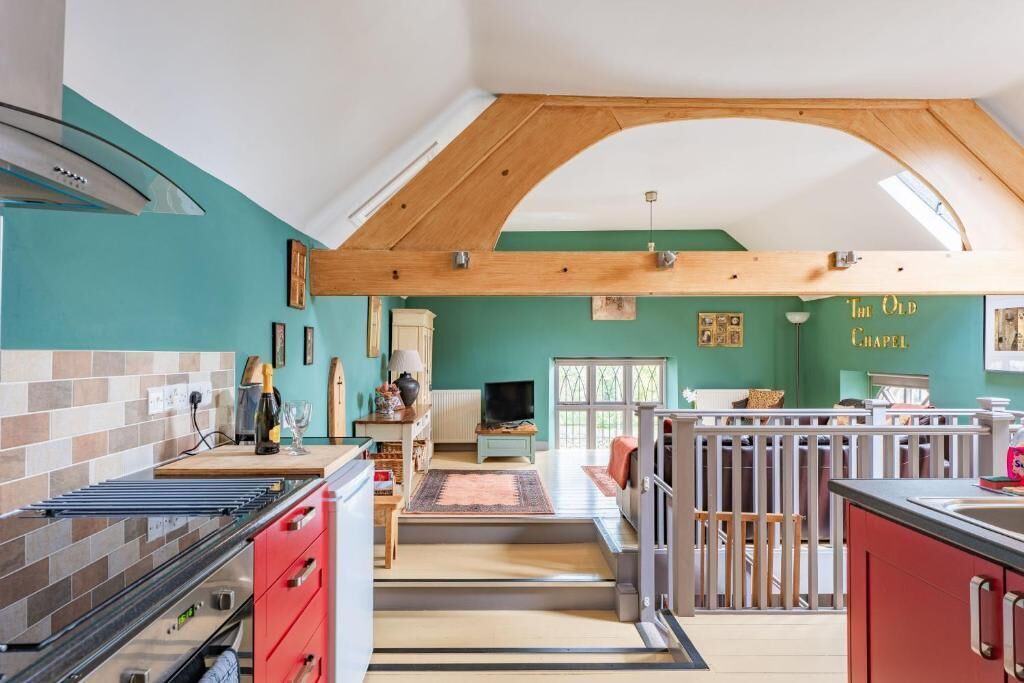 A kitchen with a modern stove, red cabinets, and a dining area with a table and chairs.