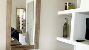 A living room with a large mirror, a wooden coffee table, and a white shelving unit with a bottle and a remote control. - Villa Merlot - private terrace and garden (Saint-Maurice-d’Ardèche)