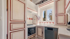 A compact kitchen with white cabinets, a built-in oven, and a dishwasher. - Villa Merlot - private terrace and garden (Saint-Maurice-d’Ardèche)