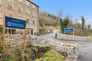 Experience the classic charm of this traditional stone building, featuring multiple windows and a scenic setting with a small stream.