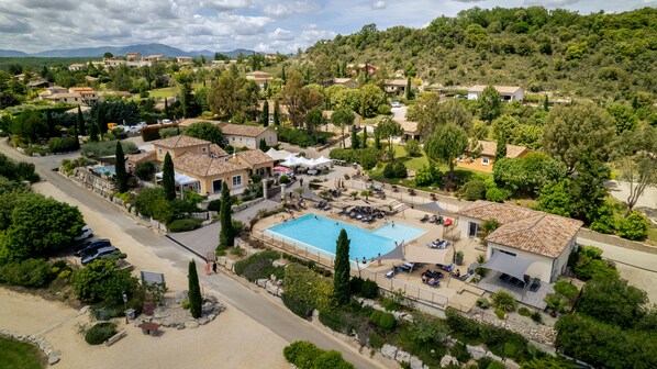 A resort with multiple buildings, a swimming pool, and lush greenery.