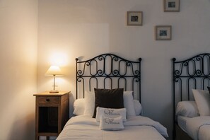 A bedroom with two beds, a nightstand with a lamp, and framed pictures on the wall.