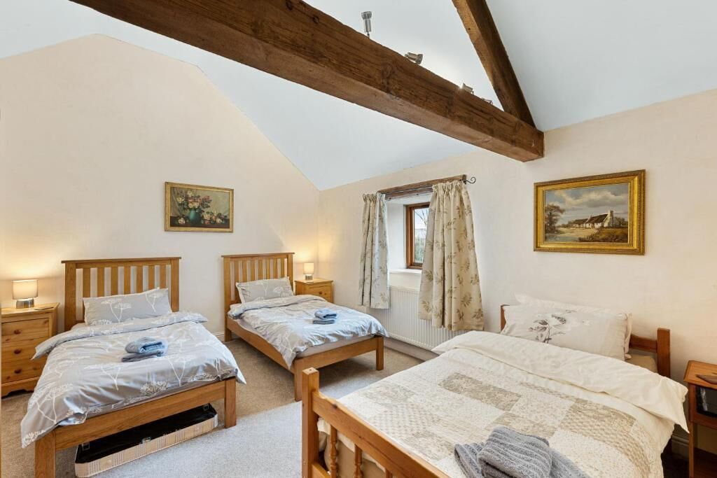 Un dormitorio con dos camas de madera, una ventana con cortinas y un cuadro en la pared.